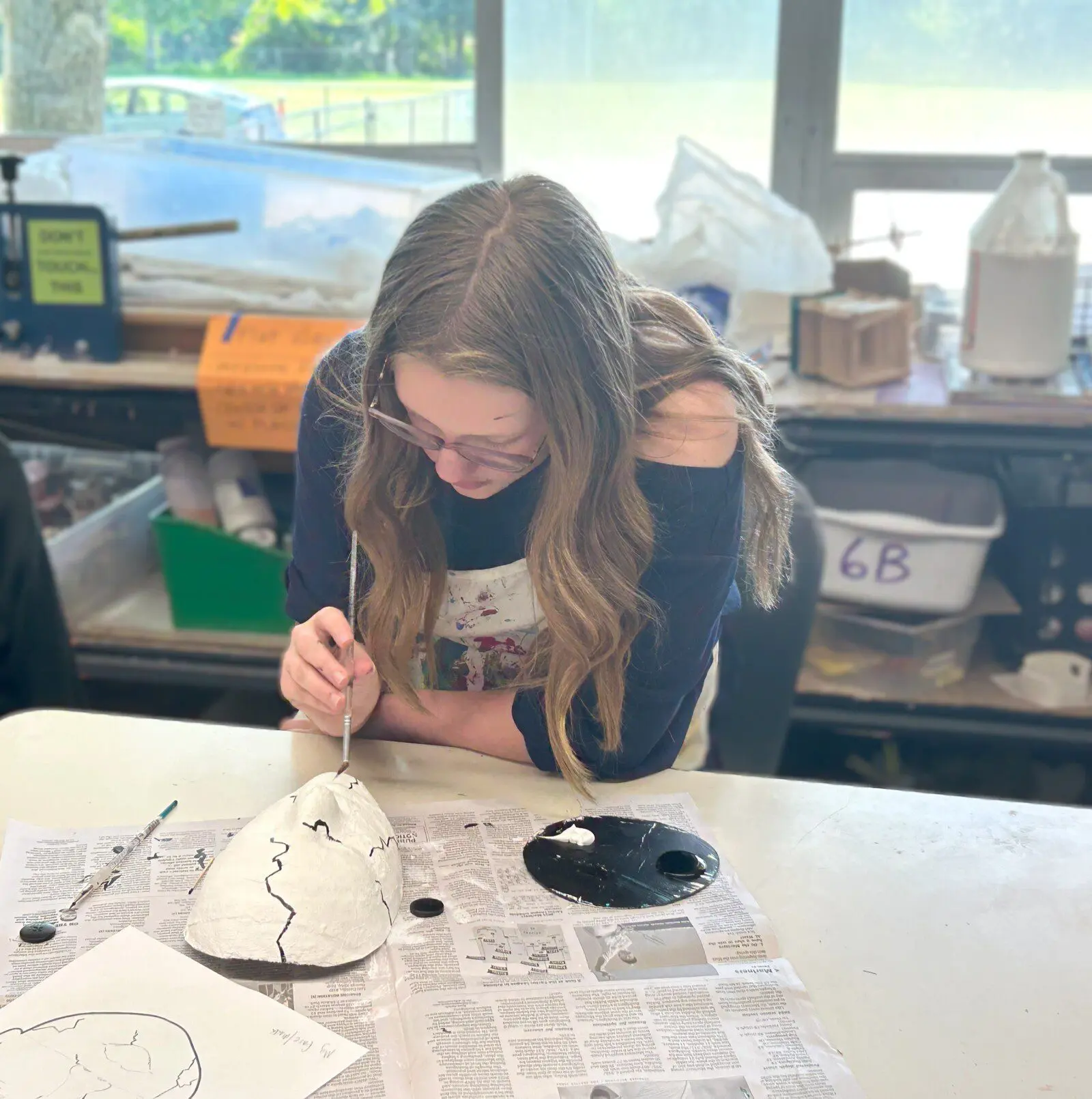 Marlo is painting her mask with a geometric design.